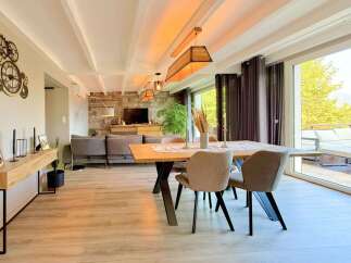 Experience modern living in this spacious open-concept dining and living area, featuring a stylish wooden dining table and comfortable seating.