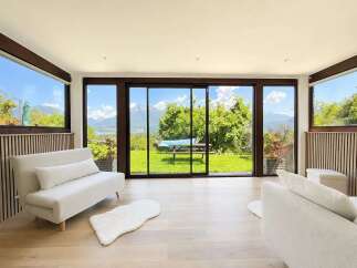 Experience breathtaking mountain and lake views from this stunning living room, featuring expansive sliding glass doors that seamlessly blend indoor and outdoor living.