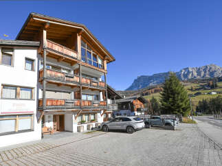 Experience alpine living in this charming property featuring a multi-story building with wooden balconies and large windows, perfect for enjoying mountain views.