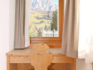 Experience breathtaking mountain views from this charming wooden desk and chair set, perfectly positioned by a large window.