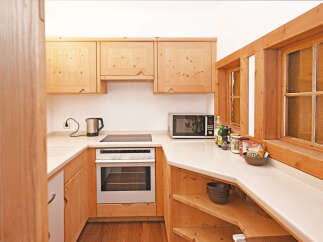 This charming kitchen features warm, natural wood cabinetry and countertops, creating a cozy and inviting atmosphere.