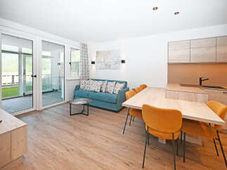 Experience modern living in this beautifully appointed apartment, featuring a comfortable teal sofa and a stylish dining area perfect for entertaining.