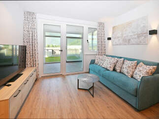 Experience modern living in this beautifully appointed living room, featuring a comfortable teal sofa adorned with floral cushions.