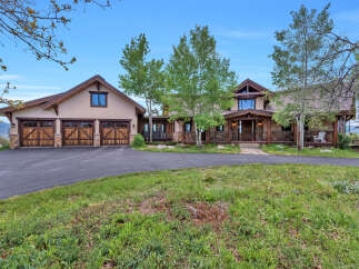 Experience luxury mountain living in this stunning estate, featuring a grand entrance with stone accents and a welcoming covered porch.