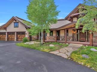 Experience luxury mountain living in this stunning home featuring a grand entrance with stone accents and a covered porch.