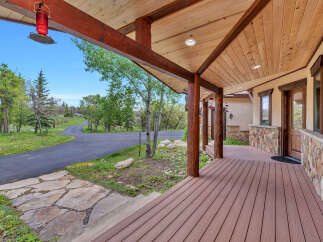 Experience rustic charm and natural beauty with this inviting covered porch, featuring warm wooden beams and a durable composite deck.