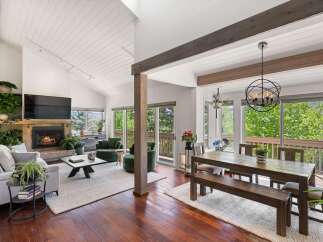 Experience breathtaking mountain views from this stunning living and dining area, featuring a cozy stone fireplace and vaulted ceilings.