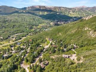 Experience luxury mountain living in this stunning aerial view of a residential area nestled amidst lush greenery and rolling hills.