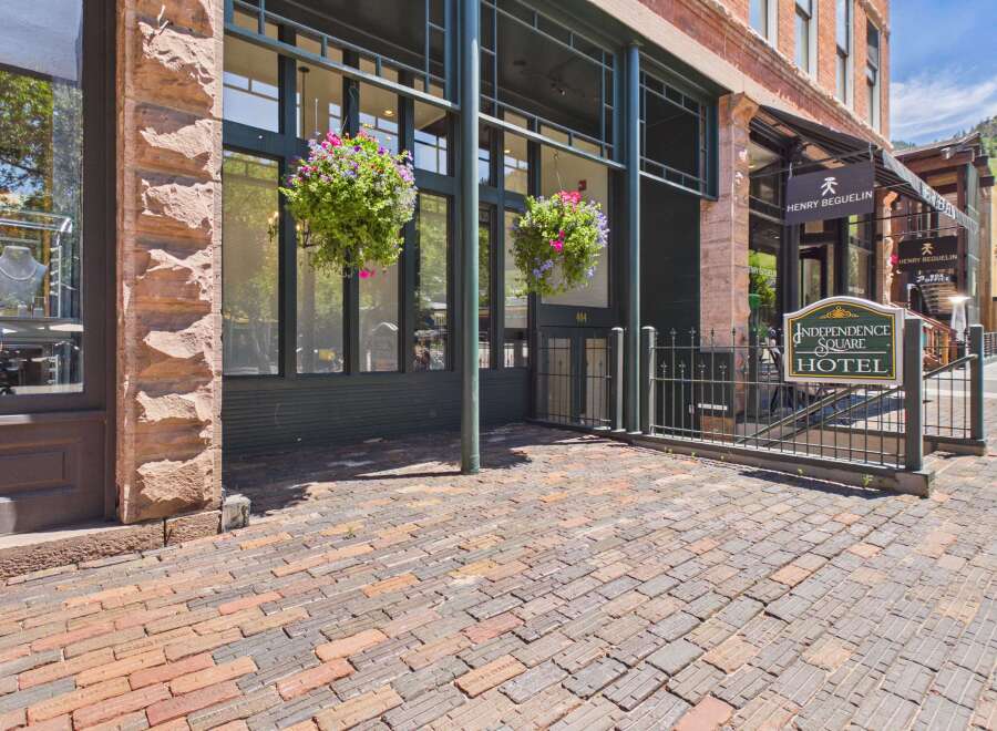 Discover the charm of this historic hotel, featuring a classic brick exterior and a welcoming entrance adorned with vibrant hanging flower baskets.