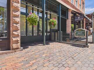 Discover the charm of this historic hotel, featuring a classic brick exterior and a welcoming entrance adorned with vibrant hanging flower baskets.
