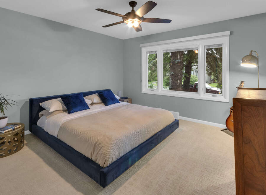 Experience comfort and style in this serene bedroom, featuring a plush navy blue bed and soft, neutral carpeting.