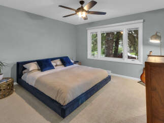 Experience comfort and style in this serene bedroom, featuring a plush navy blue bed and soft, neutral carpeting.