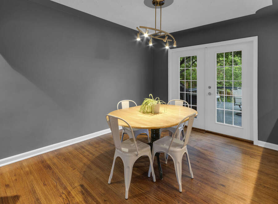 This dining area features a charming round wooden table with four white metal chairs, perfect for intimate meals.