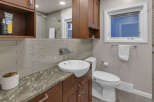 This modern bathroom features a sleek vessel sink atop a granite countertop, complemented by warm wood cabinetry.