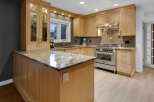 This modern kitchen boasts custom light wood cabinetry, granite countertops, and a sleek subway tile backsplash.