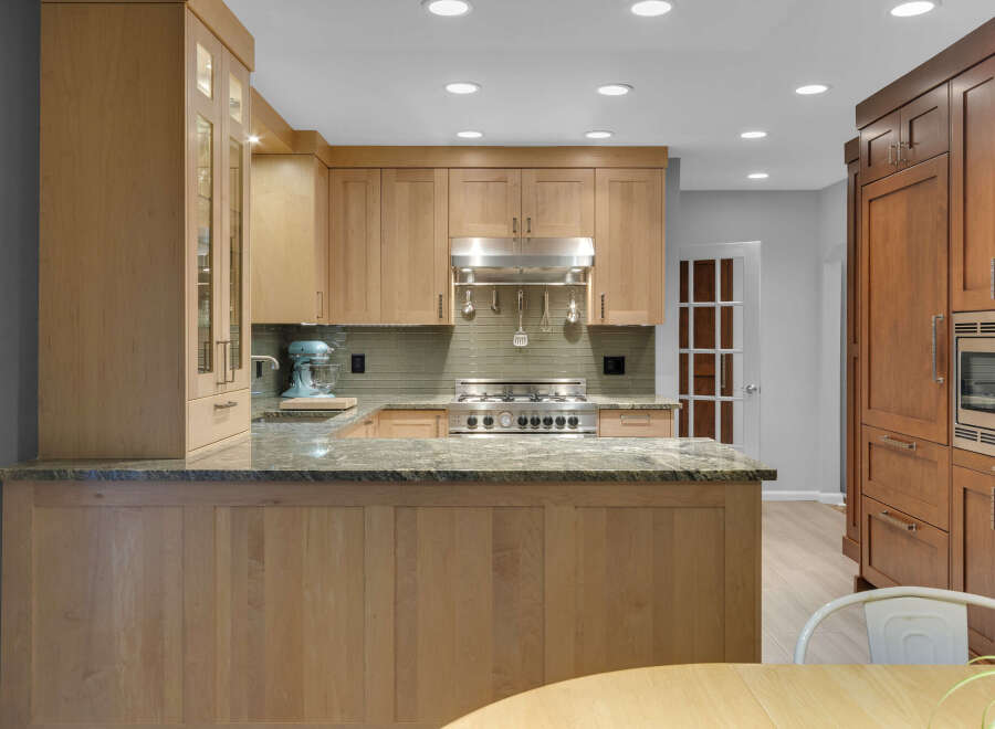 Experience culinary excellence in this stunning kitchen, featuring custom light wood cabinetry and a sleek granite countertop island.