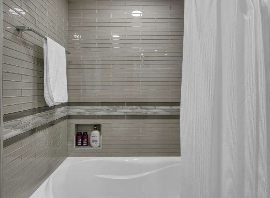 Experience modern elegance in this bathroom featuring a sleek subway tile shower surround and a decorative accent band.