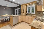 This modern kitchen boasts sleek, light wood cabinetry complemented by granite countertops and a stylish tiled backsplash.