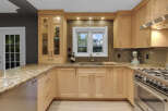 This stunning kitchen features light wood cabinetry complemented by a granite countertop and a sleek glass tile backsplash.
