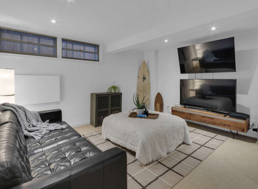 This modern living room features a sleek black leather sofa adorned with a cozy grey throw blanket, perfect for relaxing evenings.