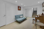 Discover comfortable living in this inviting basement space, featuring a stylish blue sofa perfect for relaxation and a beautiful wooden piano ready for musical inspiration.