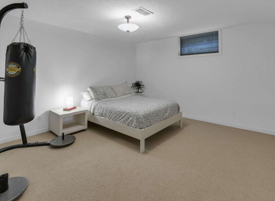 This bedroom offers a unique blend of relaxation and fitness with a comfortable bed and a professional-grade Everlast punching bag.