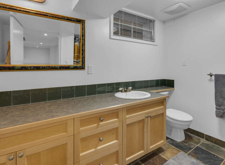This bathroom features a spacious vanity with ample storage and a clean white sink, complemented by a decorative tiled backsplash.