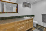 This bathroom features a spacious vanity with ample storage and a clean white sink, complemented by a decorative tiled backsplash.