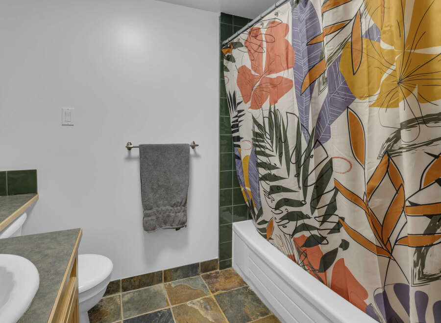 This bathroom features a stylish floral shower curtain that adds a pop of color and personality to the space.