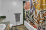 This bathroom features a stylish floral shower curtain that adds a pop of color and personality to the space.