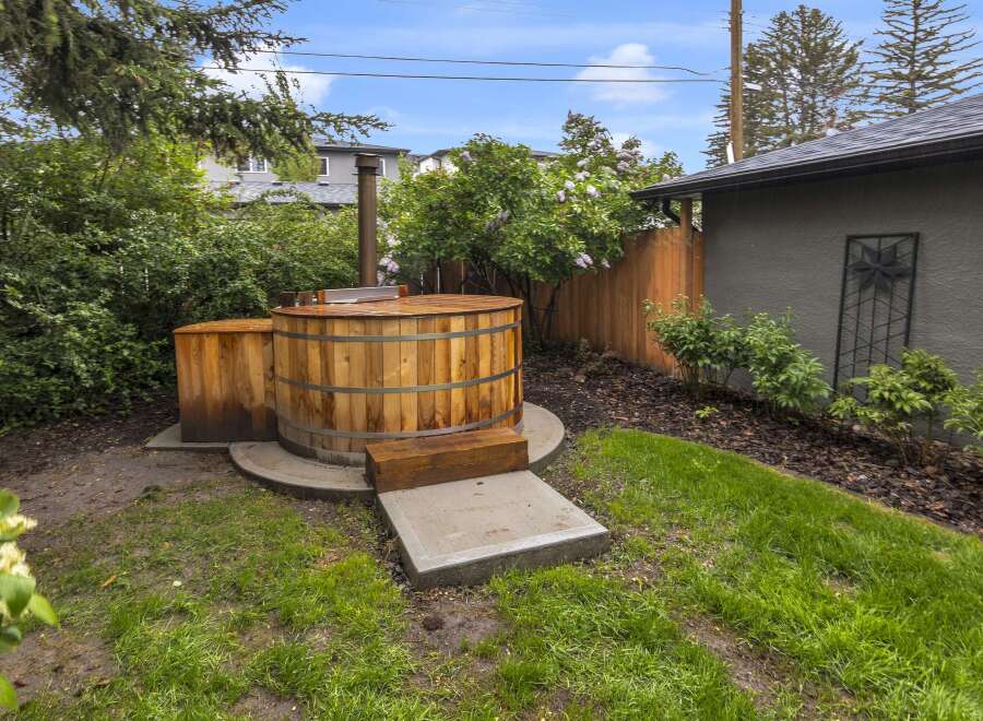 Experience ultimate relaxation in this backyard oasis featuring a charming wooden hot tub, perfect for unwinding after a long day.