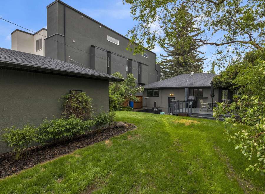 Discover this modern home with a sleek, dark exterior and a spacious backyard perfect for entertaining.