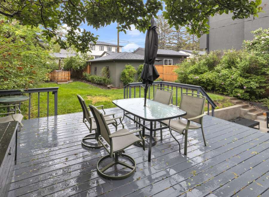 Enjoy outdoor living on this spacious deck, complete with a glass-top dining table and chairs, perfect for al fresco meals.