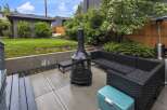 Enjoy outdoor living in this spacious backyard featuring a modern patio with a fire pit and comfortable wicker seating.