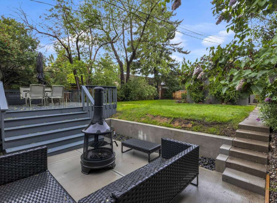 Enjoy outdoor living in this spacious backyard featuring a multi-level deck with seating and a dining area, perfect for entertaining.