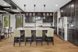 Experience luxury in this stunning kitchen featuring dark wood cabinetry, a spacious granite island with bar seating, and sleek stainless steel appliances.