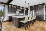 Experience luxury in this stunning kitchen featuring dark wood cabinetry, a large granite island with bar seating, and top-of-the-line stainless steel appliances.