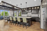 Experience luxury in this stunning kitchen, featuring dark wood cabinetry, a spacious granite island with bar seating, and a professional-grade stainless steel range hood.