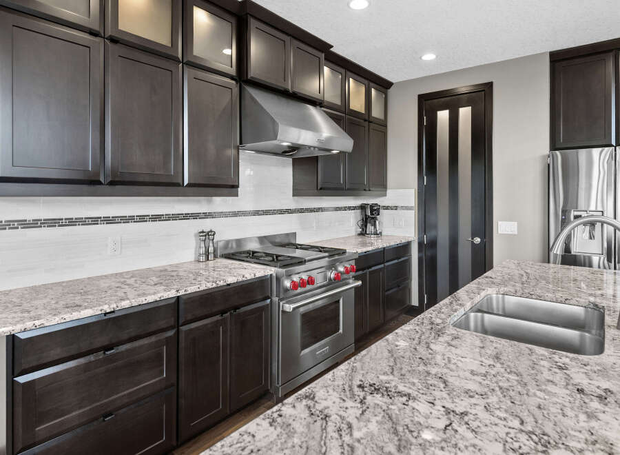 Experience luxury in this stunning kitchen, featuring sleek dark wood cabinetry and a striking granite countertop.