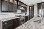 Experience luxury in this stunning kitchen, featuring sleek dark wood cabinetry and a striking granite countertop.
