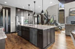 Experience luxury in this modern kitchen featuring a large granite island with a double sink and stainless steel appliances.