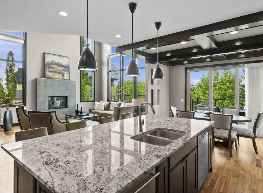 Experience luxury living in this stunning open-concept home, featuring a modern kitchen island with a double sink and granite countertops.