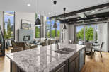Experience luxury living in this stunning open-concept home, featuring a modern kitchen island with a double sink and granite countertops.