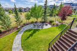 Enjoy outdoor living in this beautifully landscaped backyard featuring a stone patio with a fire pit and seating area, perfect for gatherings.