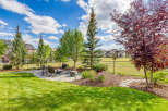 Enjoy outdoor living in this beautifully landscaped backyard featuring a spacious stone patio with comfortable seating and a fire pit, perfect for gatherings.
