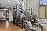 Experience modern luxury in this stunning home featuring a dramatic open-riser staircase with glass railings and dark wood accents.