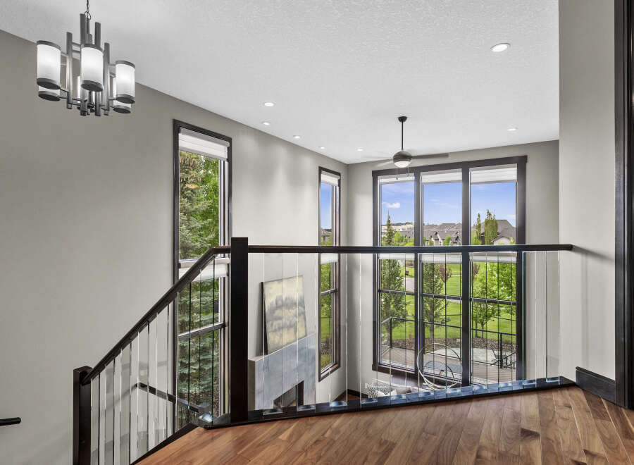 Experience modern luxury in this stunning home featuring a grand staircase with glass railings and a sleek chandelier.