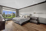 Experience luxury in this spacious master bedroom featuring a king-sized bed with a plush upholstered headboard and elegant decorative pillows.