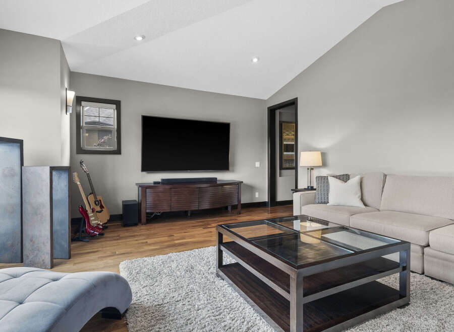 Experience modern living in this stylish living room, featuring a large flat-screen TV mounted above a sleek, dark wood media console.