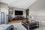 Experience modern living in this stylish living room, featuring a large flat-screen TV mounted above a sleek, dark wood media console.